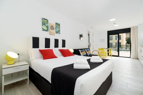 卡斯特尔德费尔斯Castell Beach Aparthotel的卧室配有带红色枕头的大型白色床