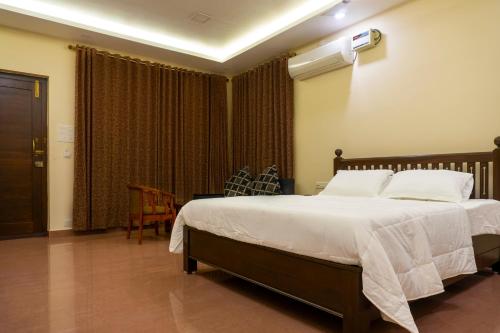 蓬蒂切里Pranaav Beach Resort的一间卧室配有一张带白色床单的大床