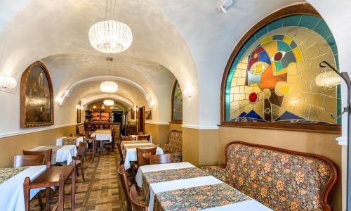 布拉格U塞尼霍奥尔拉酒店的餐厅设有桌椅和彩色玻璃窗