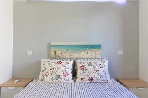 阿尔布费拉Vila - Mar - Private outdoor Jacuzzi - wifi & airco - by bedzy的一张带两个枕头的床和一幅海滩画