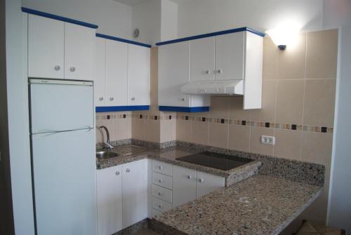 拉雷斯廷加Apartamentos Los Saltos的厨房配有白色橱柜和冰箱。