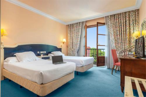 桑迪卡Hospedium Hotel Blu Sondika的酒店客房配有两张床和一张带笔记本电脑的书桌