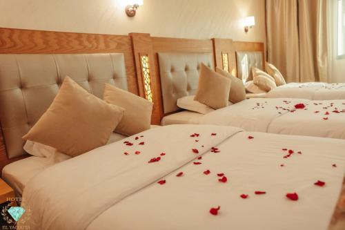 得土安伊尔雅库塔酒店的一间卧室配有两张床,床单上摆放着红色玫瑰
