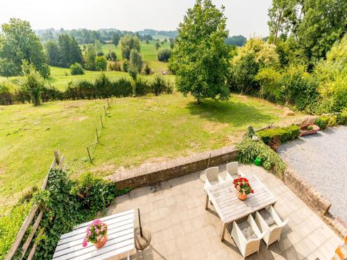 BergMagnificent Holiday Home in Sint Martens Voeren with Garden的庭院设有两把白色椅子和一张鲜花桌