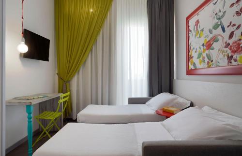 里米尼麦迪逊酒店的酒店客房设有两张床和一张桌子。