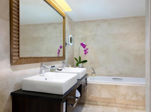 日惹日惹爱慕卡摩皇家酒店的浴室设有2个水槽、浴缸和镜子