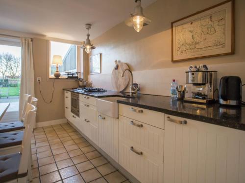 赫鲁德Spacious holiday home in Groede的厨房配有白色橱柜和黑色台面