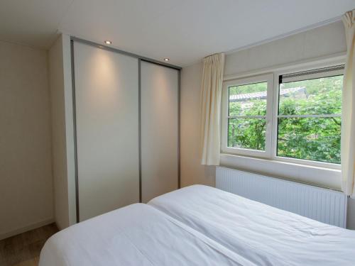德布尔特Tidy chalet with dishwasher, surrounded by forest的卧室配有白色的床和窗户。