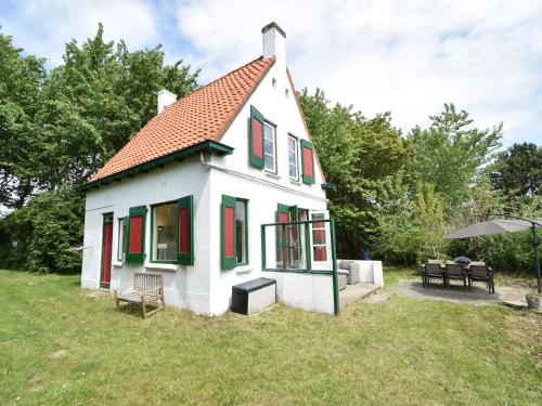 奥德多普Quintessential holiday home in Ouddorp with garden的一间白色的小房子,设有红色和绿色的窗户