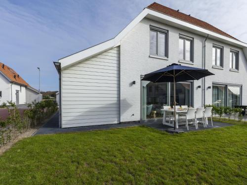 卡德赞德Luxurious villa a 5 minute walk from beach的白色的房子,配有桌子和雨伞