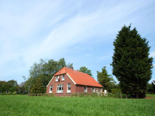 NeedeDetached farmhouse with play loft的一座红砖房子,在田野上有一个橙色的屋顶