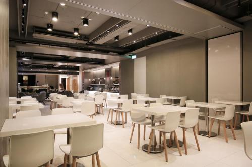 台北丹迪旅店大安森林公园店的一间设有白色桌椅的用餐室