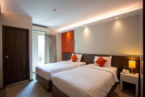曼谷Lemontea Hotel Bangkok - SHA Extra Plus的橙色墙壁的酒店客房内的两张床