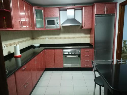 阿雷西费Vivienda compartida Tajaraste的厨房配有红色橱柜和不锈钢冰箱