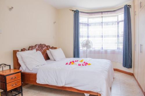 内罗毕JKIA homestays的一间卧室配有一张带白色床单的床和一扇窗户。