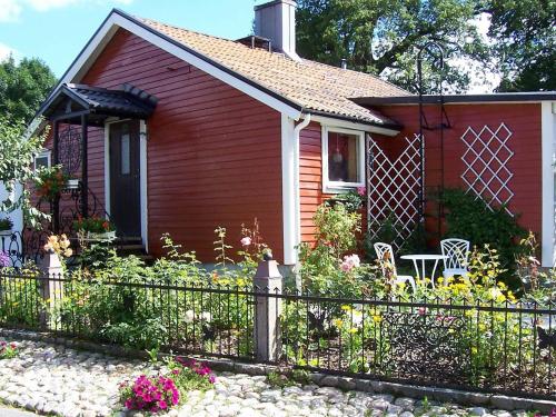 海斯勒霍尔姆5 person holiday home in H SSLEHOLM的一座红色的小房子,带围栏和鲜花