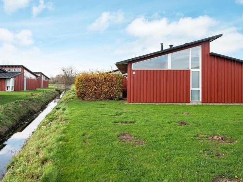 博恩瑟6 person holiday home in Bogense的草场上红色的外墙房子