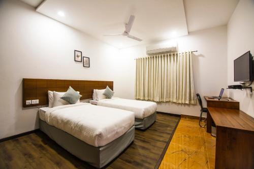 海得拉巴Skyla Serviced Apartments的酒店客房设有两张床和一台平面电视。