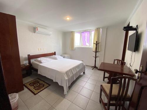 累西腓广场酒店的一间卧室配有一张床、一张桌子和一张书桌
