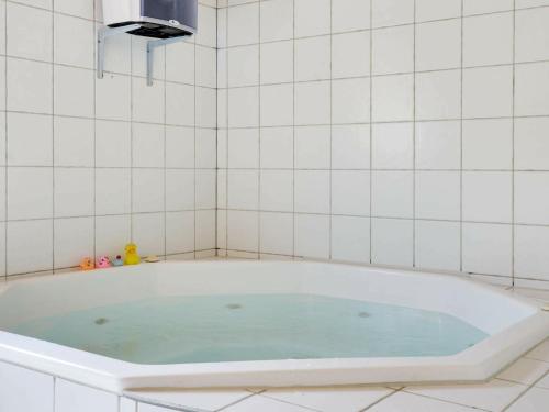亨讷斯特兰德8 person holiday home in Henne的白色瓷砖浴室设有蓝色水浴缸