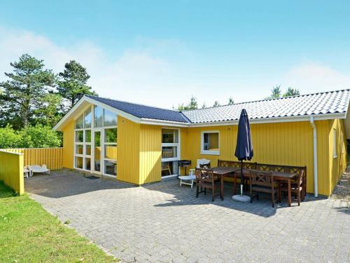 亨讷斯特兰德8 person holiday home in Henne的黄色的房子,配有野餐桌和雨伞