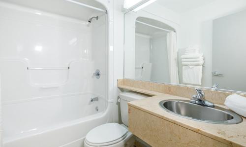魁北克市Repotel Aéroport Québec的浴室配有盥洗盆、卫生间和浴缸。