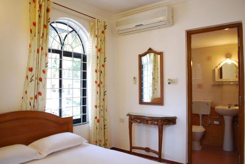 坎多林Albuquerque BetterHomes, Goa的一间卧室配有床、水槽和镜子