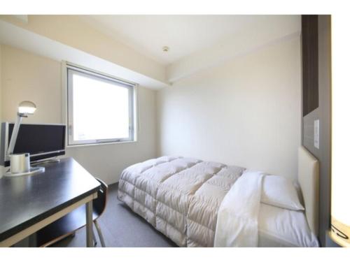 八王子市R&B HOTEL HACHIOJI - Vacation STAY 13862v的一间卧室配有一张床、一张书桌和一个窗户。
