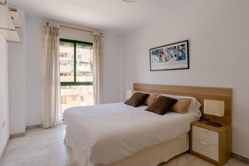 多列毛利诺斯Apartamento Residencial Bajondillo的白色的卧室设有床和窗户
