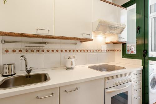 多列毛利诺斯Apartamento Residencial Bajondillo的白色的厨房设有水槽和炉灶。