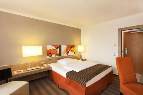 美因河畔法兰克福H4法兰克福展览中心酒店的酒店客房配有一张床、一张桌子和一把椅子。
