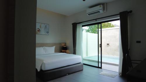 洛坤府Toledo Pool Villa的一间卧室设有一张床和一个滑动玻璃门