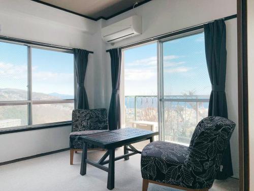 伊东荘荘旅馆的客厅配有桌椅和窗户。