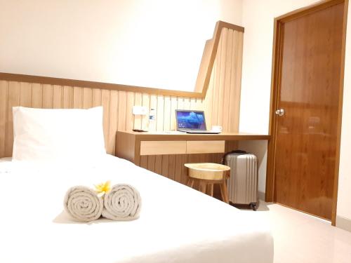 三宝垄Hotel Pantes Kota Lama Semarang的卧室配有白色的床和一张书桌上的笔记本电脑