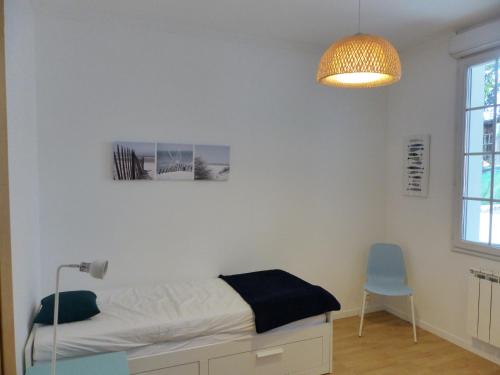 奥瑟戈尔Villa Mitoyenne Pour 4 Personnes Proche Centre-Ville D hossegor的一间卧室配有一张床、一盏灯和一把椅子