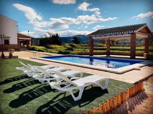 阿尔奇多纳Casa Rural Huerta Abuela María的一组白色躺椅,位于游泳池旁