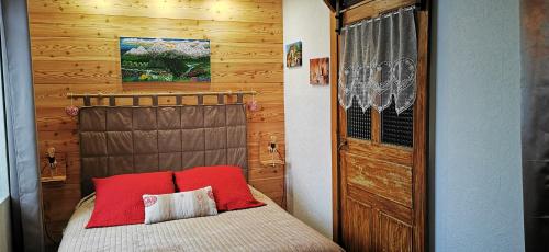 GrignonLa grange de Lina的一间卧室配有一张带红色枕头的床和木墙