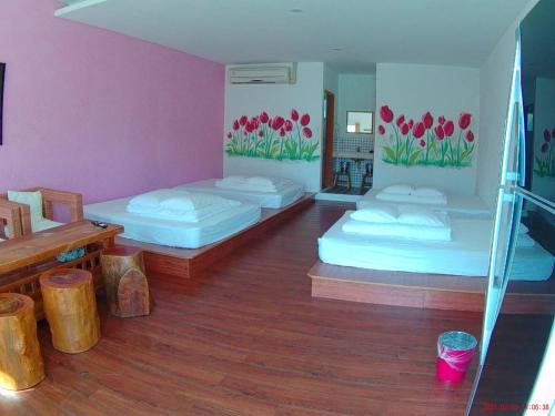 鹅銮鼻捻花民宿的配有2张床的客房铺有木地板,墙上挂有鲜花