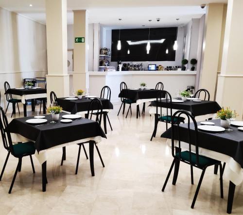 纳瓦尔卡内罗希达德纳瓦尔卡内罗酒店的一间设有黑色桌椅的餐厅和一间厨房