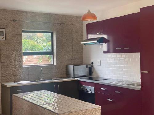约翰内斯堡Elegant84的厨房配有紫色橱柜、水槽和窗户