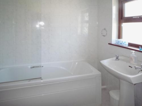 卡斯尔巴Clydagh Lodge的白色的浴室设有浴缸和水槽。