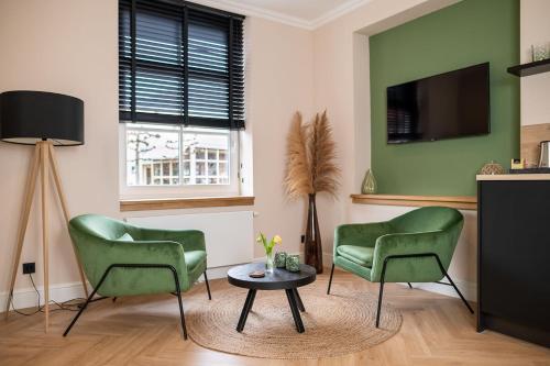 巴勒哈姆斯泰德Bed en Baguette的客厅配有两张绿色椅子和一张桌子