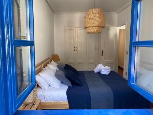 塔索内斯Apartamento San Miguel的一间卧室配有一张带蓝色床单的床和两个窗户。
