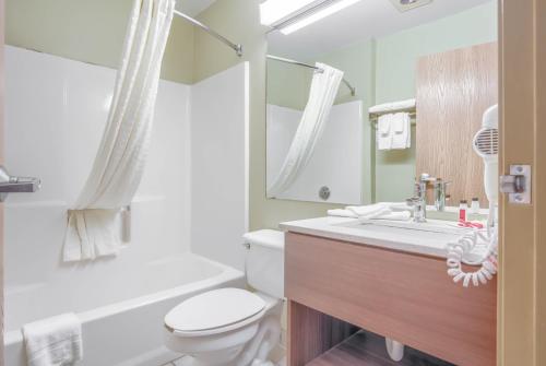 格尔夫海岸米克罗温德姆湾岸酒店的一间带卫生间、水槽和镜子的浴室