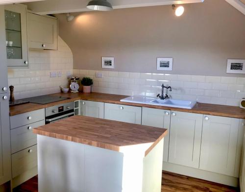 滨海韦斯顿Hill Cottage的厨房配有白色橱柜和水槽