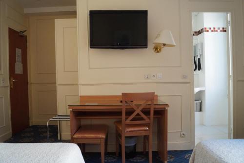 巴黎Hotel Havane Opera的一间设有一张桌子的房间,墙上有一台电视机