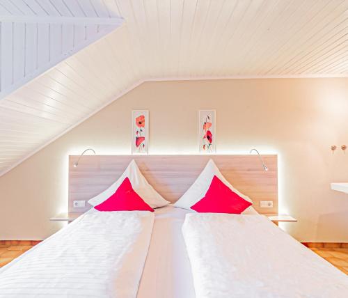 Mesenich约翰尼舍夫葡萄酒咖啡厅和旅馆的卧室配有带红色枕头的大型白色床