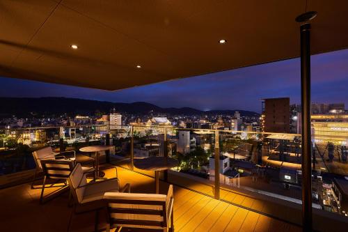 京都The Gate Hotel Kyoto Takasegawa by Hulic的阳台,晚上可欣赏到城市景观