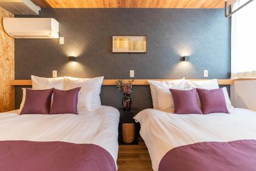 大阪Alla Scuderia Bijou Suites的两张位于酒店客房的床,配有紫色和白色枕头