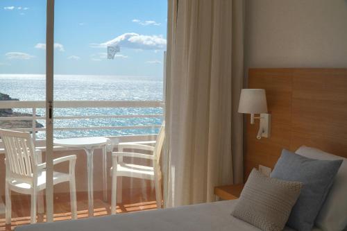 萨洛Hotel Cala Font的一间卧室配有一张床,享有海景